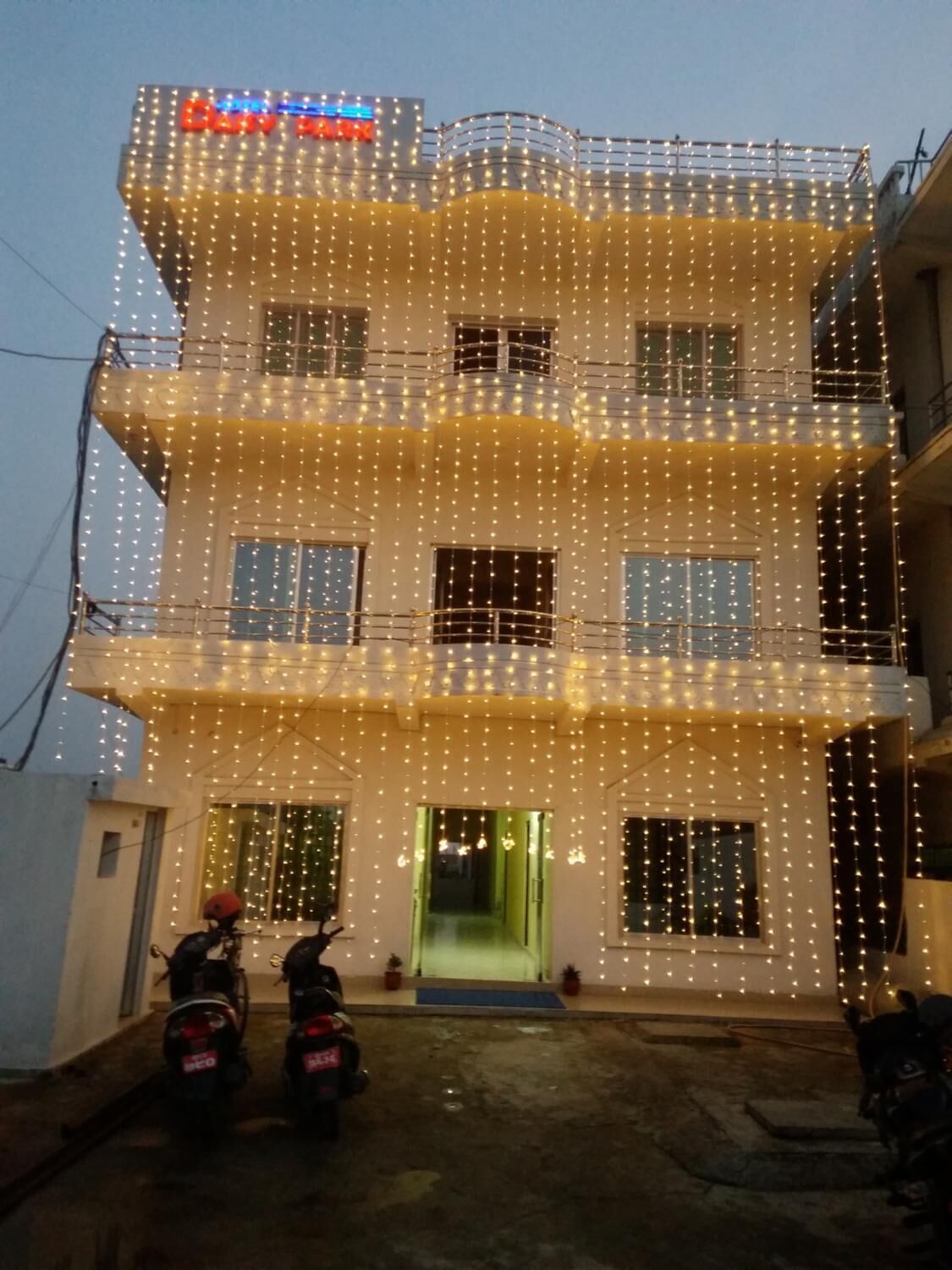 A multi-story building with balconies, string lights, and a green entrance door.