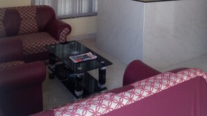 Una sala de estar con sofá, una mesa de centro, televisor y ventilador de techo.