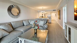 A modern living room with a sofa, a coffee table, and a decorative mirror.