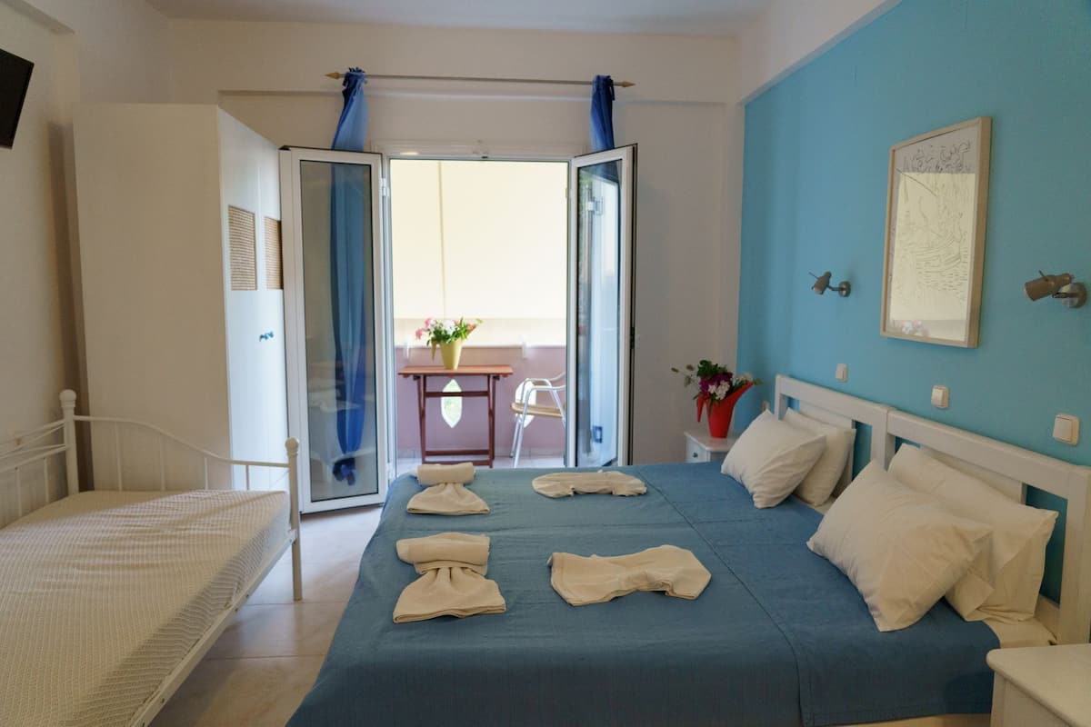 Ein Schlafzimmer mit Bett, Schreibtisch und einem Balkon mit Stuhl.