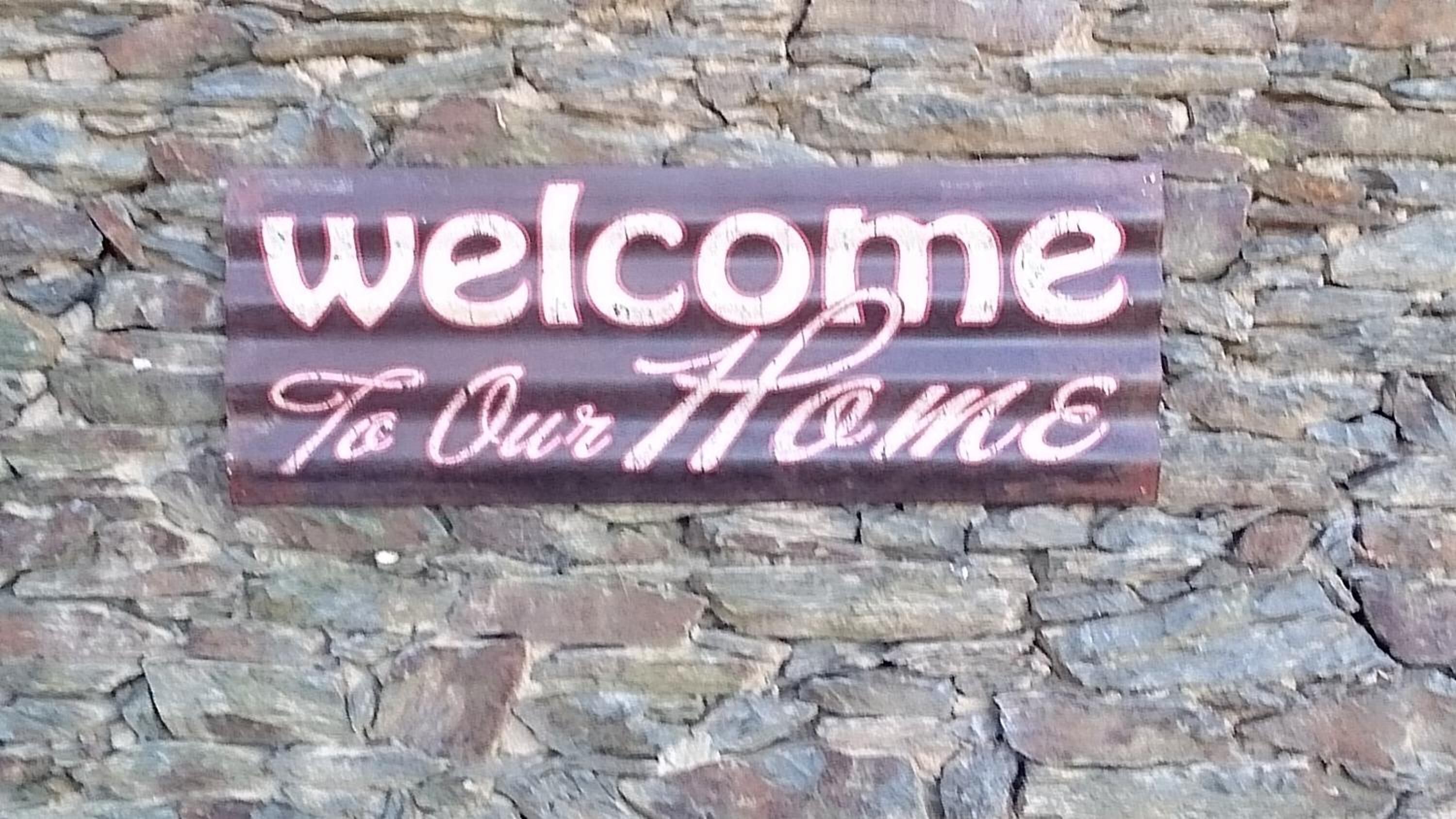 A welcome sign against a stone wall.