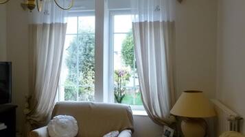 A cozy living room with a sofa, a lamp, and a window with curtains.