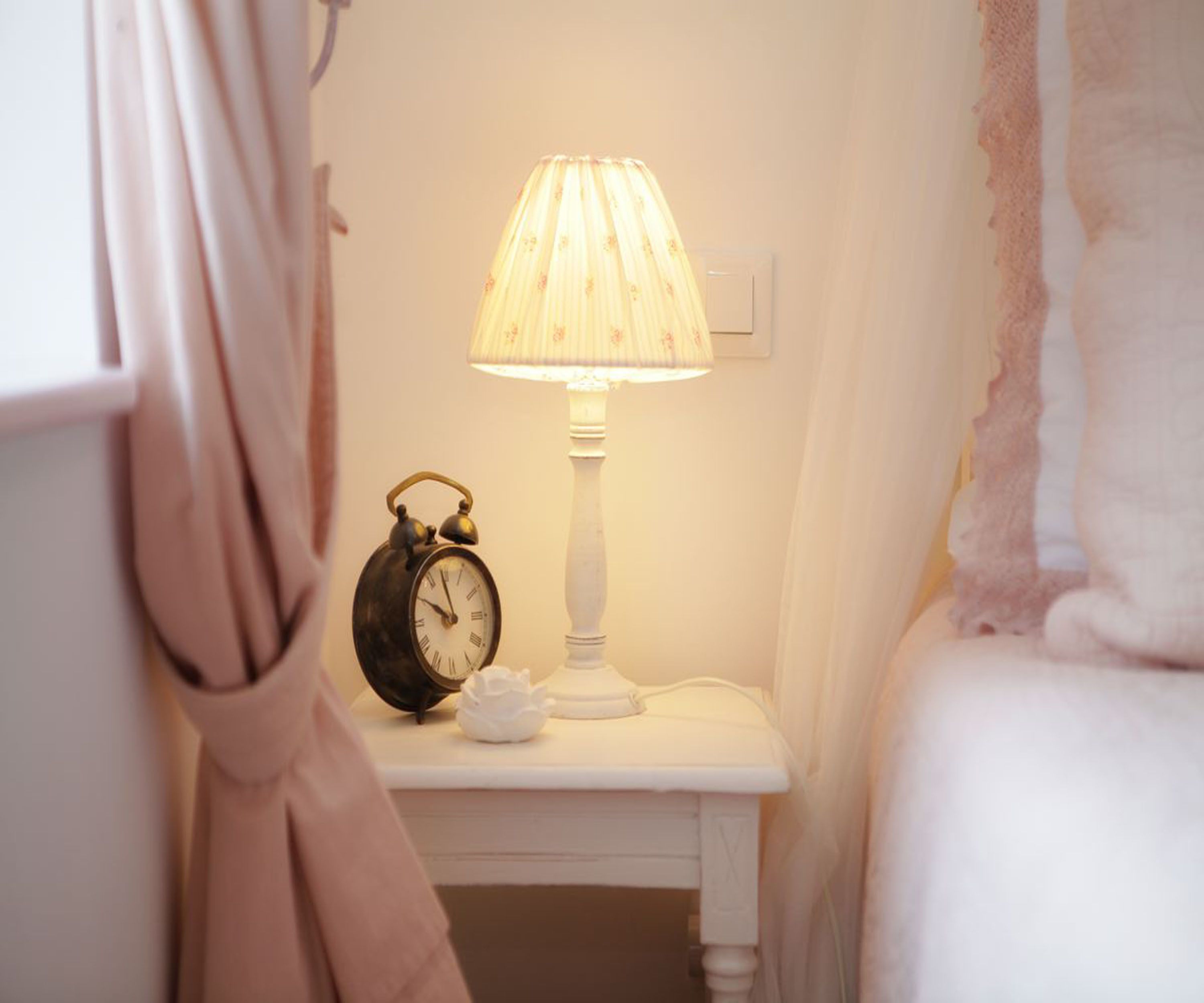 A bedside table with a lamp and an alarm clock.