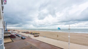 Un paseo marítimo frente a la playa con vista al mar, un estacionamiento y un edificio con un letrero.