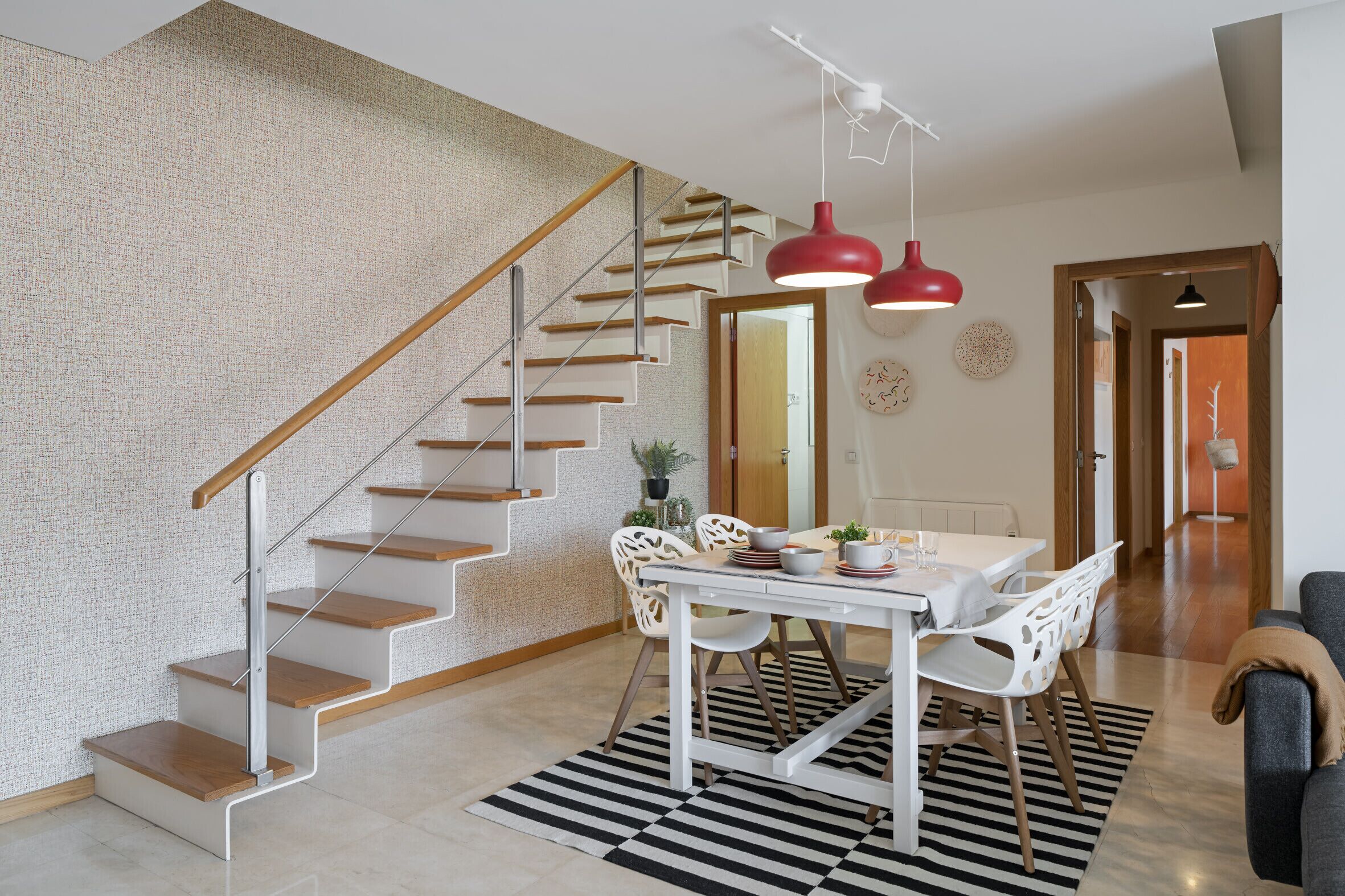 A modern interior with a staircase, dining area, and a living space.