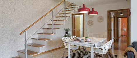 A modern interior with a staircase, dining area, and a living space.