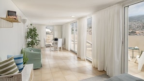 A spacious living area with a balcony, a dining table, and a seating arrangement.
