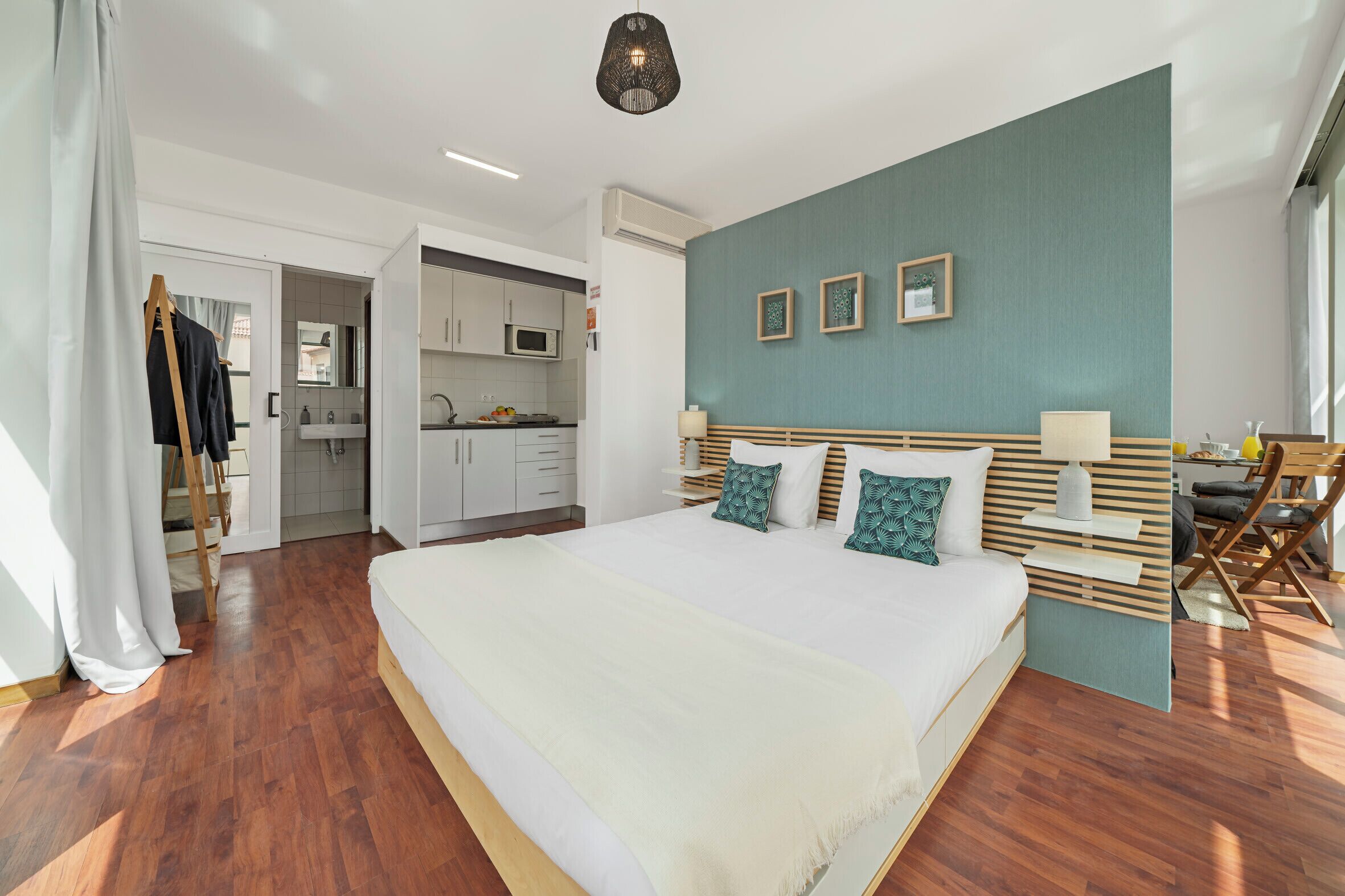 Un dormitorio moderno con una cama grande, kitchenette y comedor.