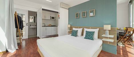 Un dormitorio moderno con una cama grande, kitchenette y comedor.