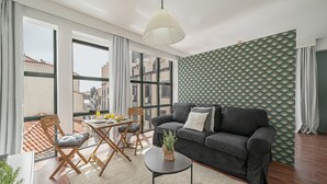 A modern living room with a dark grey sofa, a round coffee table, and a large window offering a city view. - Pelourinho III, studio in Funchal (Funchal)