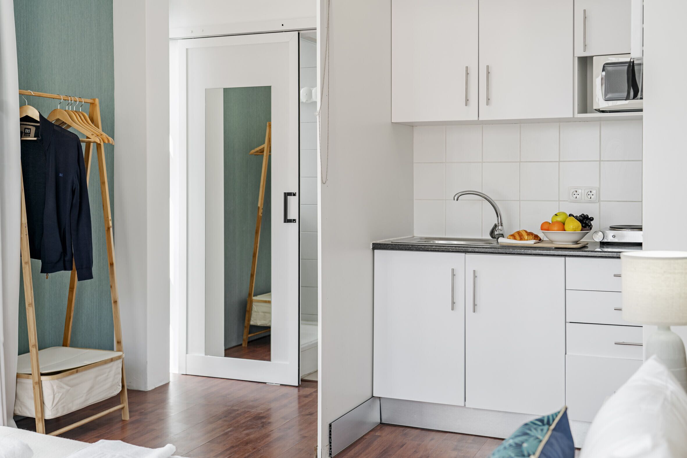 A compact kitchen with white cabinets, a microwave, and a sink.