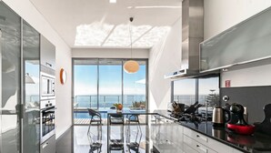 A modern kitchen with a glass dining area overlooking a pool and ocean. - Fonte do Mar 1 - Four Bedroom Villa, Sleeps 8 (Caniço)