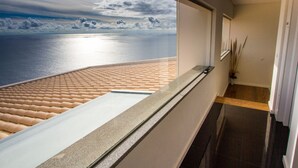 A corridor with a glass wall offering a view of a beach and ocean. - Fonte do Mar 1 - Four Bedroom Villa, Sleeps 8 (Caniço)