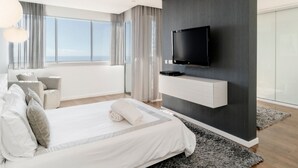 A modern bedroom with a large bed, a mounted TV, and a view of the outdoors. - Fonte do Mar 1 - Four Bedroom Villa, Sleeps 8 (Caniço)
