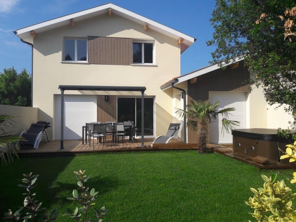Une maison à deux étages dotée d’un patio couvert, d’un espace barbecue et d’une pelouse bien entretenue.
