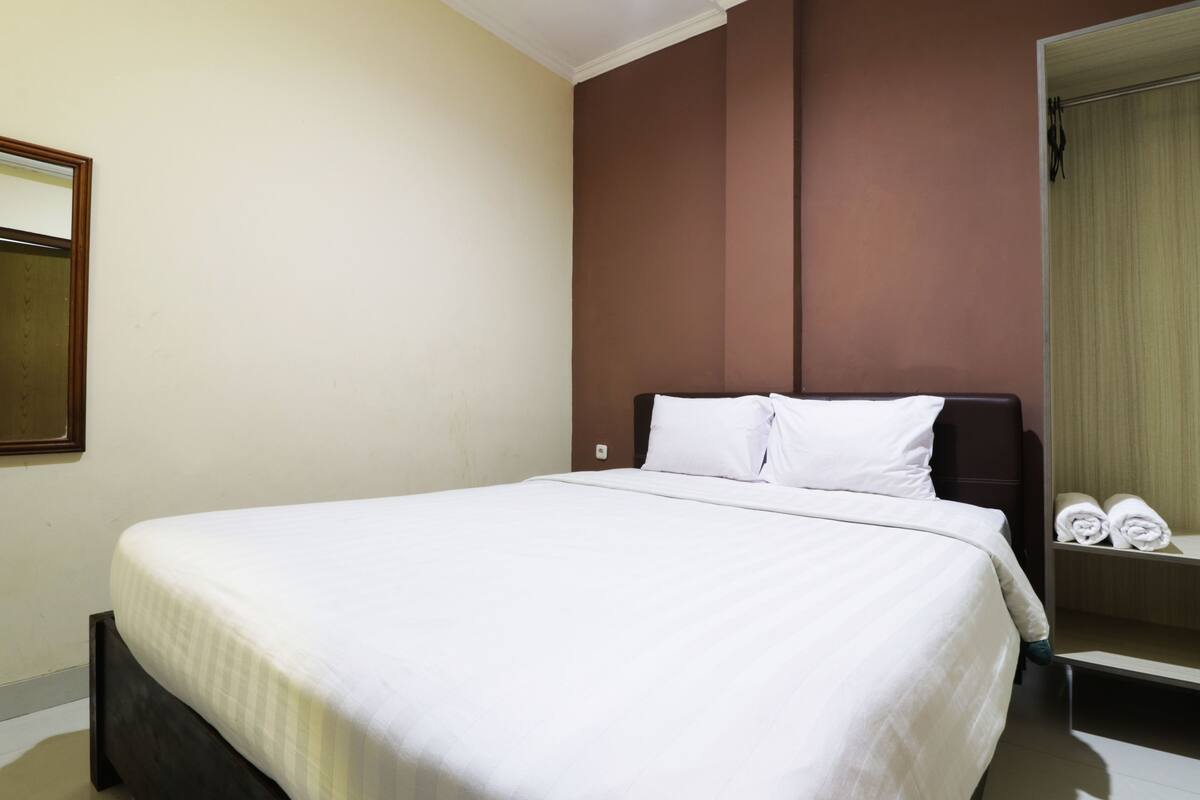 Ein Hotelzimmer mit einem großen Bett, einem Kleiderschrank und einem Spiegel.