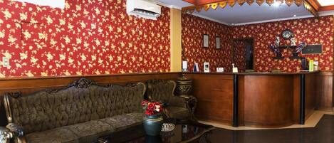 A lobby with a sofa, a reception desk, and a clock on the wall.