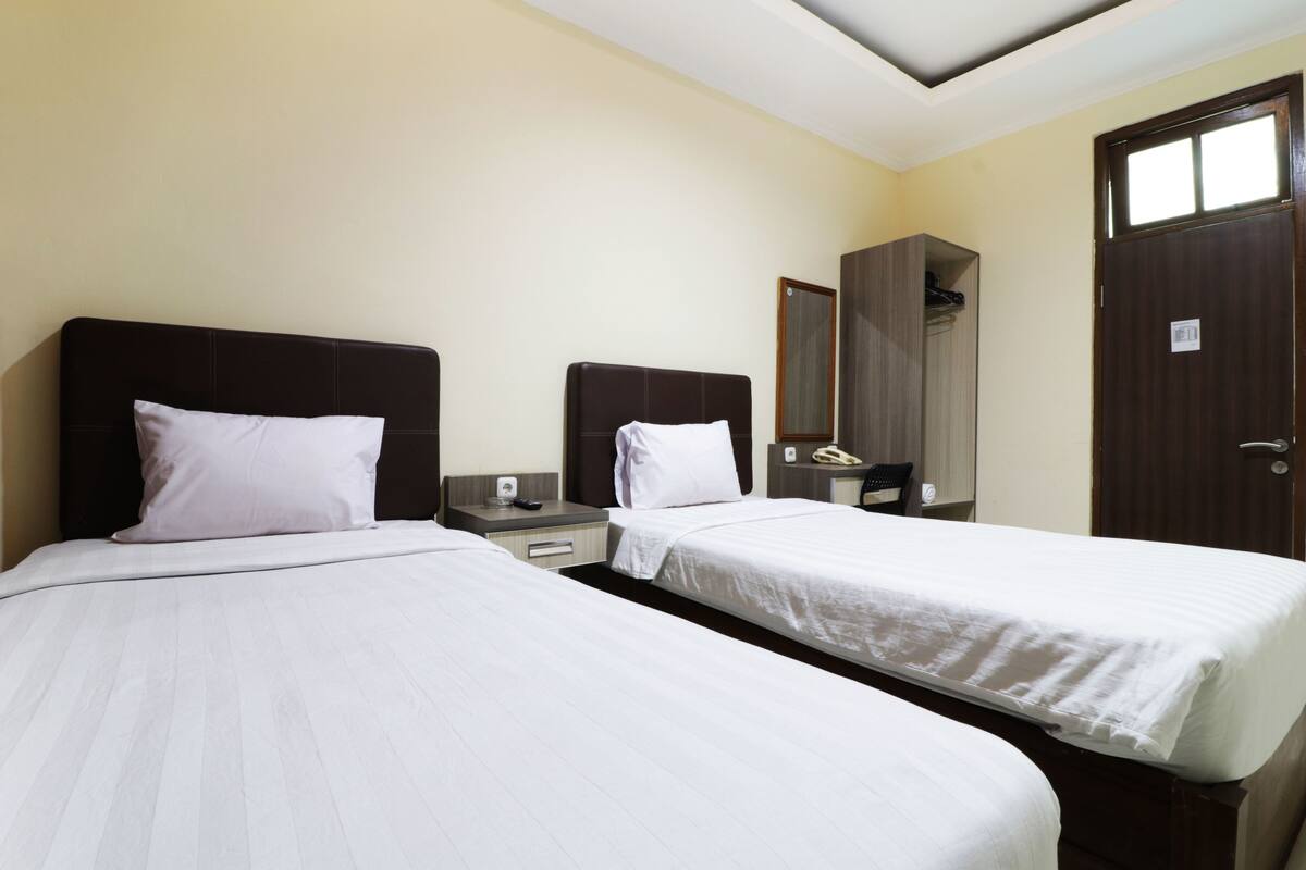 Ein Hotelzimmer mit zwei Betten, einem Kleiderschrank, einem Spiegel und einer Tür.