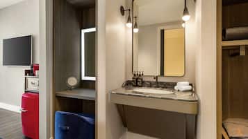 A modern bathroom with a large mirror, a sink, and a red suitcase.