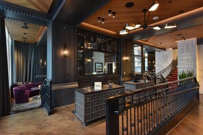 A lobby with a reception desk, a staircase, and a seating area with purple sofas. - Canopy by Hilton San Francisco SoMa (San Francisco)