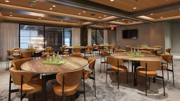 A conference room with multiple round tables and chairs, equipped with water bottles and a chandelier.