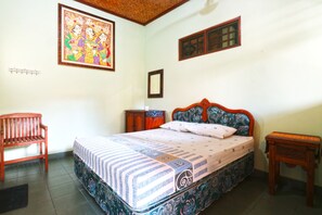 A bedroom with a bed, a wooden bench, a small table, and a wall-mounted shelf. - Bamboo Inn Kuta (Kuta)
