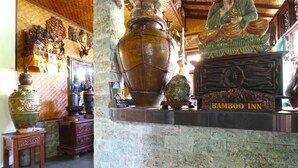 A traditional interior with a large urn, a Buddha statue, and a sign reading "Bamboo Inn." - Bamboo Inn Kuta (Kuta)