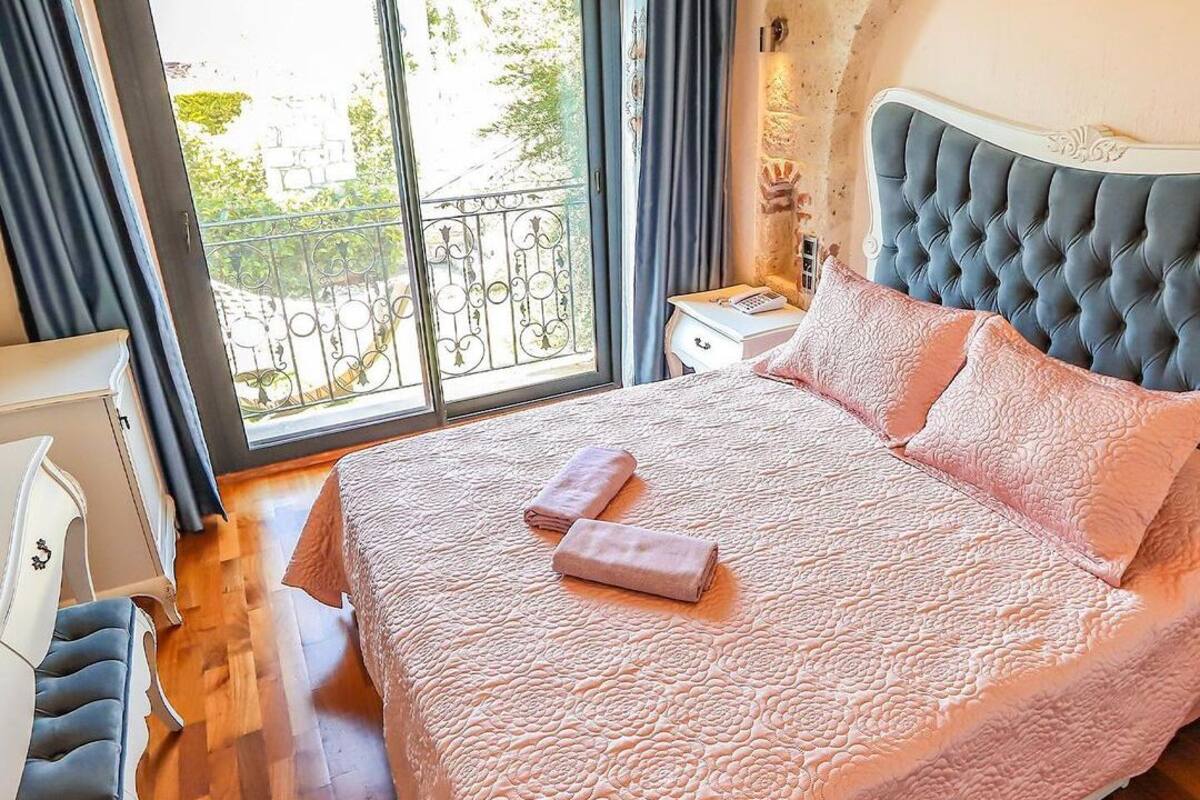A bedroom with a large bed, a nightstand, a chair, and a view of the outside balcony.