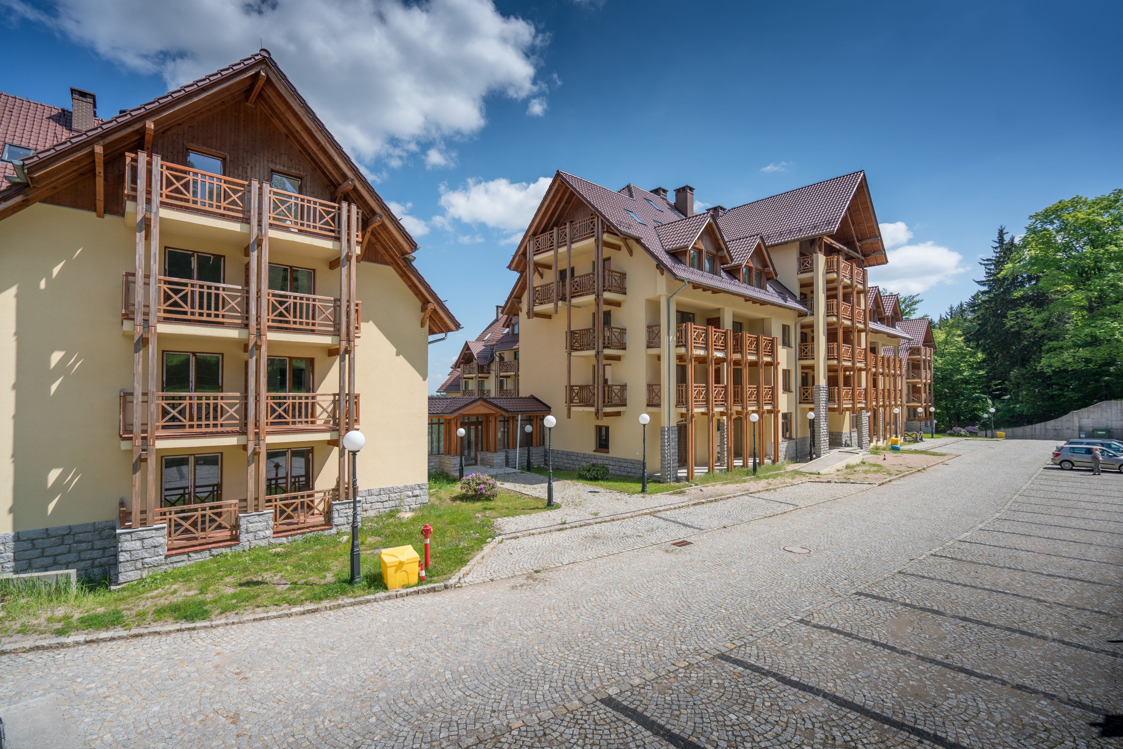 A row of multi-story buildings with balconies, a cobblestone street, and a clear sky.