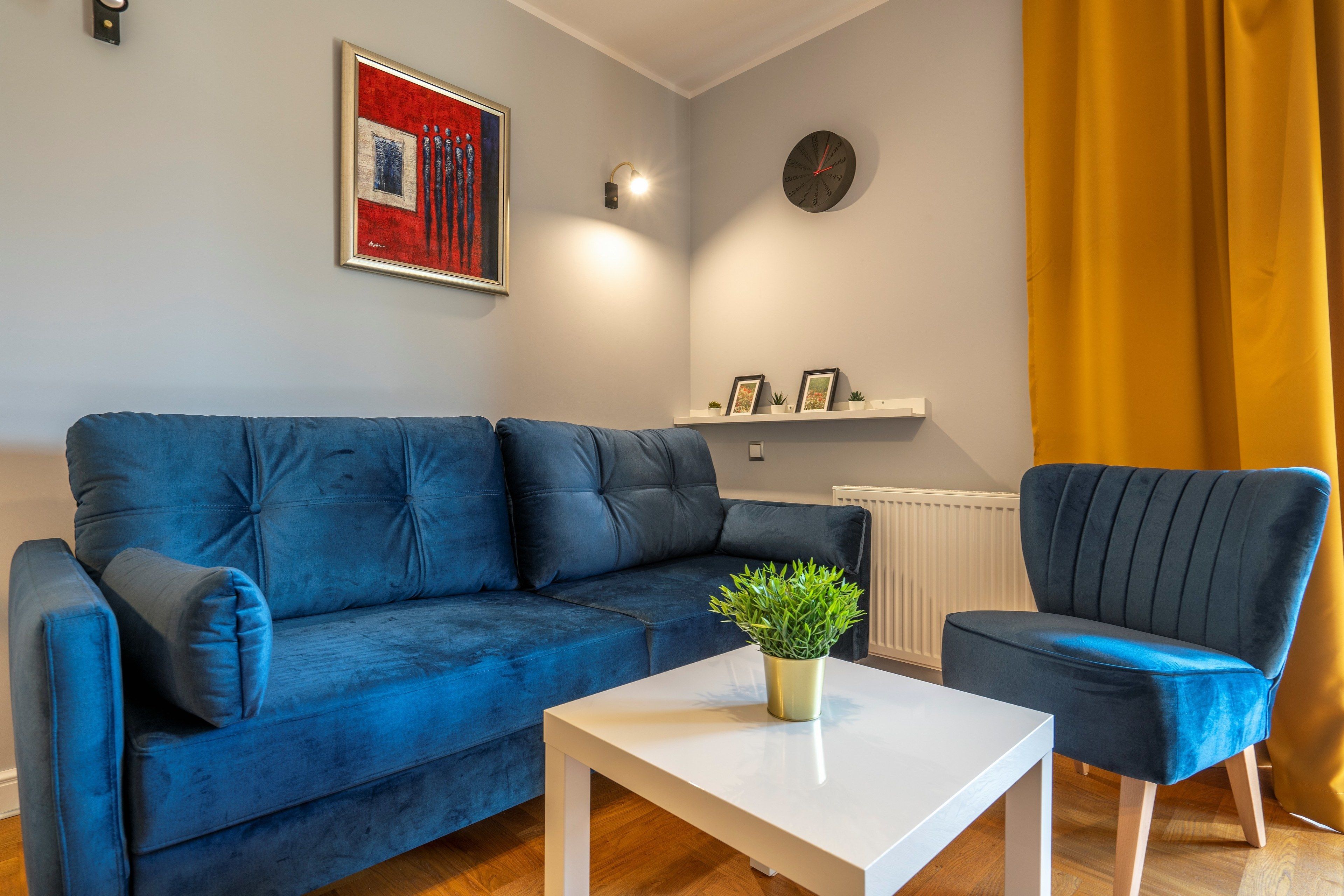 Een woonkamer met een blauwe bank, een witte salontafel en een donker fauteuil.