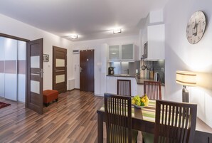 A modern kitchen with white cabinets, a coffee machine, and a clock on the wall.