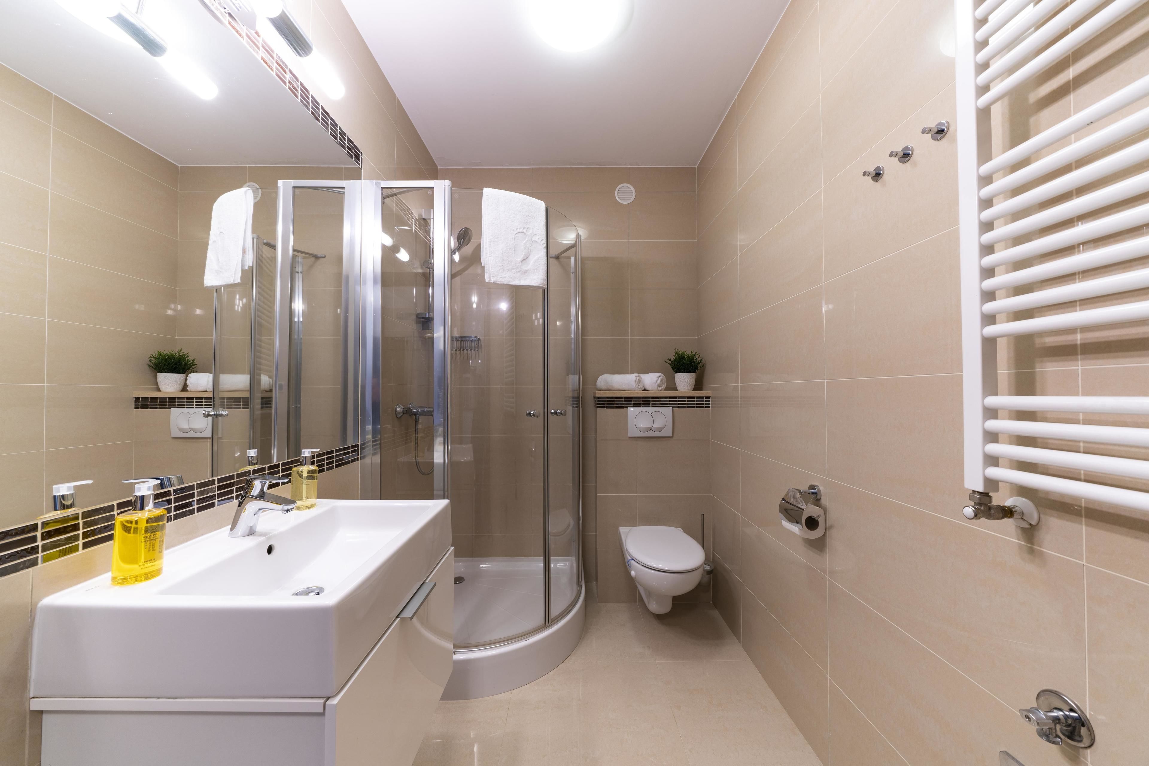 Uma casa de banho moderna com cabine de duche em vidro, lavatório branco com espelho e sanita.