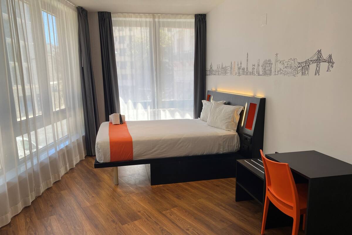 Une chambre d’hôtel avec un lit, un bureau et une chaise.