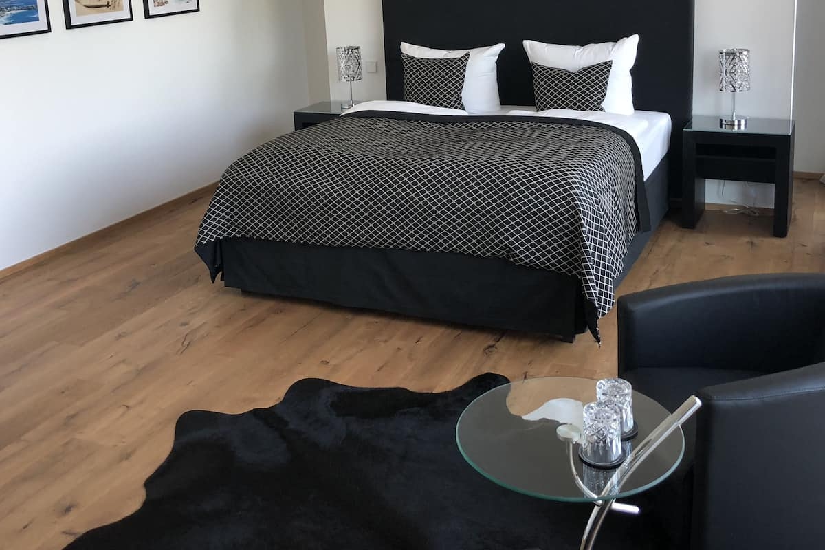 Quarto moderno com colcha estampada em preto e branco, cabeceira preta e duas luminárias de cabeceira. Há três quadros na parede.