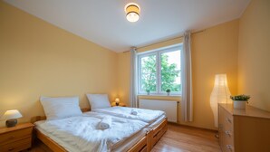 A bedroom with a wooden bed, bedside tables, a dresser, a window with curtains, and a radiator. - RentPlanet - Apartament Mickiewicza (Szklarska Poreba)