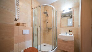 A modern bathroom with a glass-enclosed shower, a toilet with a wooden seat, and a sink with a mirror above it. - RentPlanet - Apartament Mickiewicza (Szklarska Poreba)