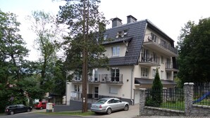 A multi-story residential building with a balcony on the second floor, a garage, and a fenced yard with a slide. - RentPlanet - Apartament Mickiewicza (Szklarska Poreba)