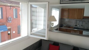 Una cocina con armarios de madera, un lavamanos y una ventana con vista a la calle.