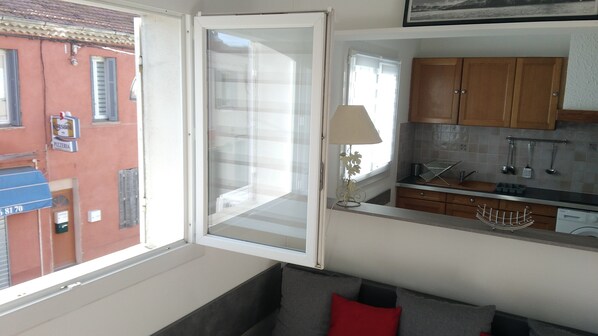 A kitchen with wooden cabinets, a sink, and a window overlooking a street.