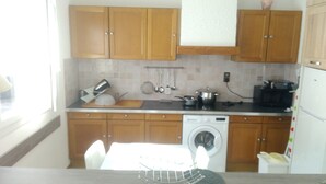 Cocina compacta con muebles de madera, lavadora y electrodomésticos básicos.
