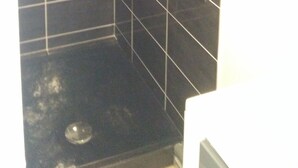 Un pequeño box de ducha con azulejos, equipado con ducha de mano y rociador manual.
