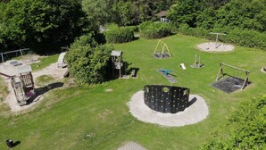 An aerial view of a playground with various play structures, including a swing set, a climbing frame, and a seesaw. - Feriendorf Waldbrunn (Waldbrunn)
