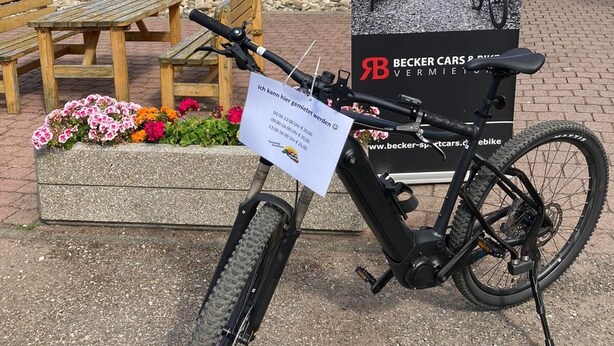 A bicycle parked in front of a building with a sign advertising e-bikes. - Feriendorf Waldbrunn (Waldbrunn)