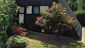 A black wooden house with a triangular roof and a large window. - Feriendorf Waldbrunn (Waldbrunn)