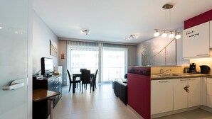 A modern kitchen with a dining area, a small island, and a view of the outside. - Jersey 201 (Koksijde)