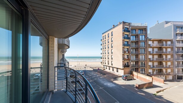 A balcony with a view of the beach and adjacent buildings. - Jersey 201 (Koksijde)