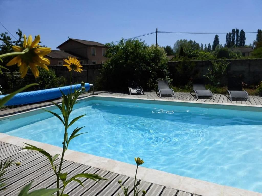 A swimming pool with lounge chairs and a wooden deck.