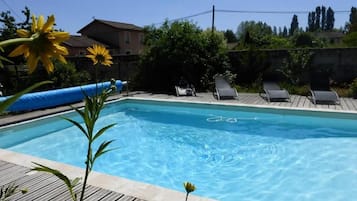 A swimming pool with lounge chairs and a wooden deck.