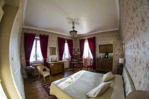 Un dormitorio con una cama grande, un aparador, una silla y un escritorio.