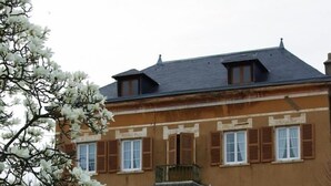 A two-story building with a symmetrical facade, a central entrance with a staircase, and a balcony on the upper floor. - Le Clos des Tanneurs (Taponas)